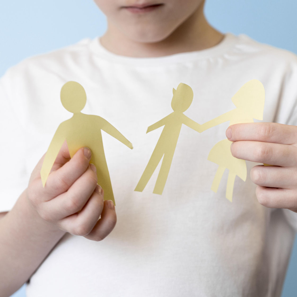Niño sosteniendo figuras de papel recortadas que representan a sus padres separados, simbolizando el impacto del divorcio en los hijos.